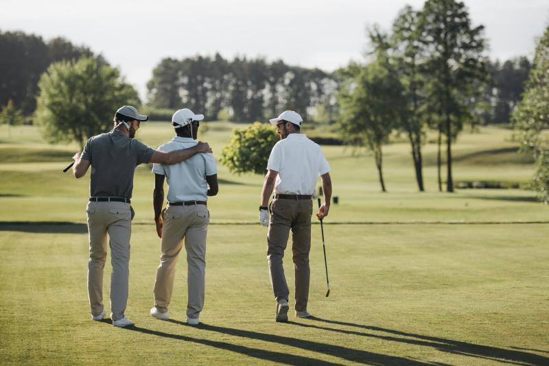 3 men walking on golf course